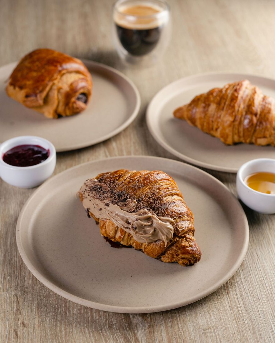 Croissants y un pain au chocolat en platos con café